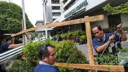 Petugas membongkar seng-seng yang menghiasi depan gerai Starbucks, Jalan MH Thamrin, Jakarta, Jumat (15/1). Seng yang dipaku pada kayu-kayu itu dibongkar petugas. (Liputan6.com/Faizal Fanani)