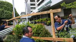 Petugas membongkar seng-seng yang menghiasi depan gerai Starbucks, Jalan MH Thamrin, Jakarta, Jumat (15/1). Seng yang dipaku pada kayu-kayu itu dibongkar petugas. (Liputan6.com/Faizal Fanani)