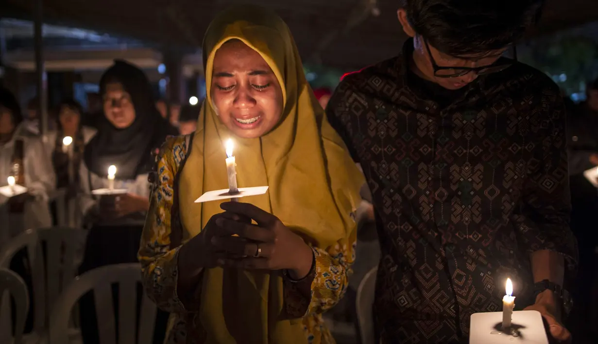 Umat muslim meneteskan air mata ketika mengikuti doa bersama lintas agama saat peringatan setahun tragedi bom gereja Surabaya di luar Gereja Katolik Santa Maria Tak Bercela, Senin (13/5/2019). Pada peringatan itu digelar juga doa lintas agama yang dihadiri sejumlah pemuka agama. (Juni Kriswanto/AFP)