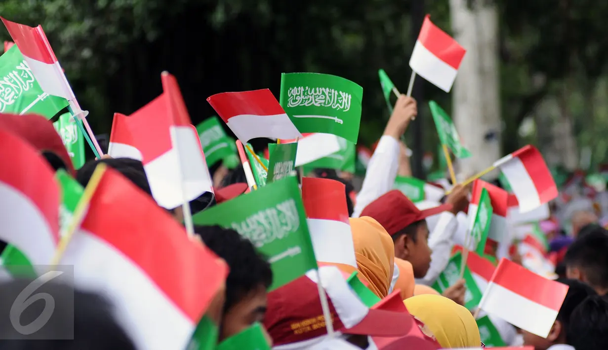 Sejumlah pelajar mengibarkan bendera kedua negara untuk menyambut kedatangan Raja Salman bin Abdulaziz di sekitar Istana Bogor, Rabu (1/3). 21 dentuman meriam dan kibaran bendera kedua negara mewarnai sambut Raja Salman. (Liputan6.com/Helmi Fithriansyah)