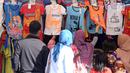 Pengunjung memilih kaus cenderamata di kawasan Monumen Nasional, Jakarta, Senin (25/12). Libur perayaan Natal dimanfaatkan warga untuk berwisata di kawasan Monumen Nasional. (Liputan6.com/Helmi Fithriansyah)