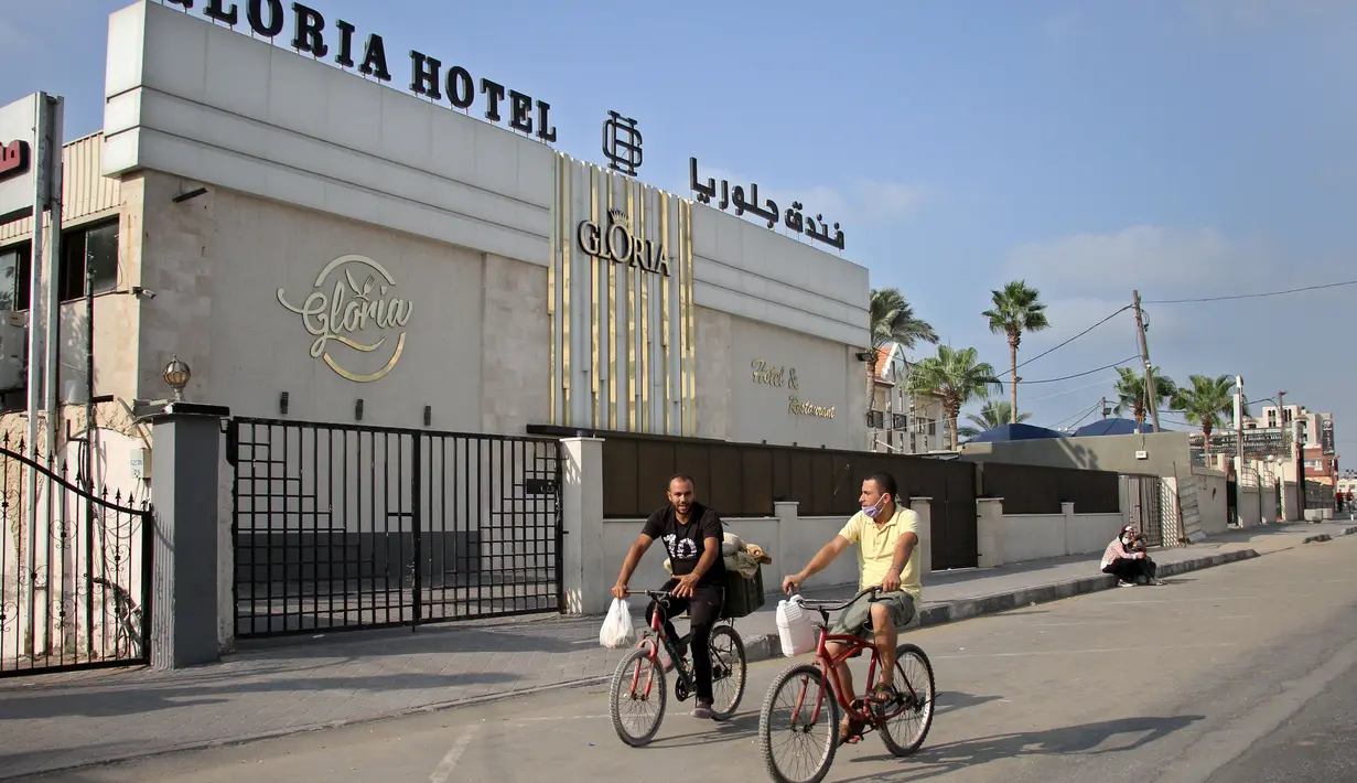 Warga Palestina bersepeda melewati sebuah hotel di Gaza City, 17 September 2020. Lebih dari 500 tempat wisata di Gaza, termasuk hotel, restoran, gedung pernikahan, dan kafe, telah ditutup menyusul penerapan lockdown yang menyebabkan 7.000 pekerja menganggur sementara. (Xinhua/Rizek Abdeljawad)