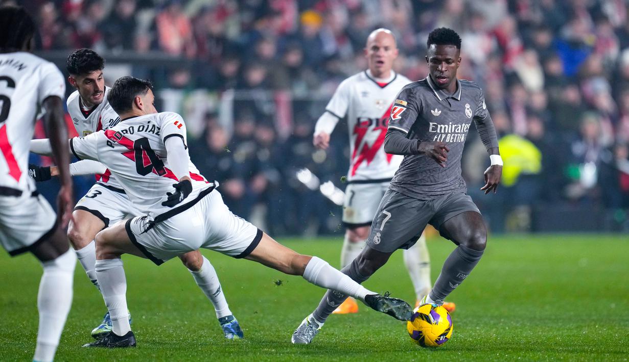 Pemain Real Madrid, Vinicius junior, berusaha melewati pemain Rayo Vallecano pada laga Liga Spanyol di Campo de Futbol de Vallecas, Minggu (15/12/2024) dini hari WIB. (AP Photo/Manu Fernandez)