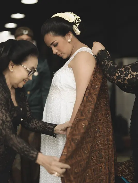 Angel juga mengenakan dress putih tanpa lengan dan dibalutkan kain batik warna coklat. Dengan aksesori antingnya.  [@angelpieters]