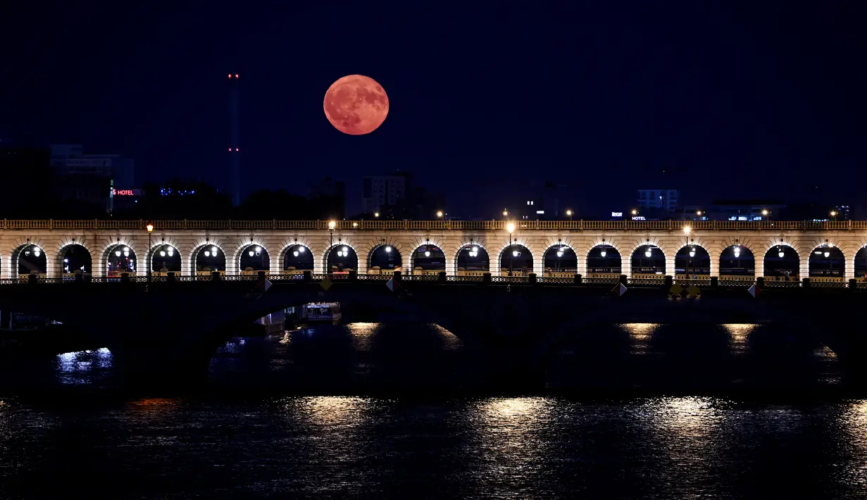 Foto yang diambil di Paris pada 3 Juli 2023 ini menunjukkan supermoon Juli, yang dikenal sebagai Buck Moon, dengan 'Pont de Bercy' di latar depan.
(Stefano RELLANDINI / AFP)