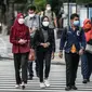 Sejumlah warga menyeberang jalan di kawasan Jalan Thamrin, Jakarta, Selasa (17/5/2022). Presiden Joko Widodo atau Jokowi mengatakan, masyarakat diperbolehkan tidak menggunakan masker jika sedang beraktivitas di luar ruangan atau area terbuka yang tidak padat orang. (Liputan6.com/Faizal Fanani)