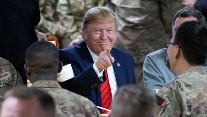 Presiden Amerika Serikat Donald Trump menunjuk sambil makan bersama para tentara di Pangkalan Udara Bagram, Afghanistan, Kamis (28/11/2019). Kunjungan dadakan Trump pada hari Thanksgiving tersebut mengejutkan pasukan AS yang bertugas di Afghanistan. (AP Photo/Alex Brandon)