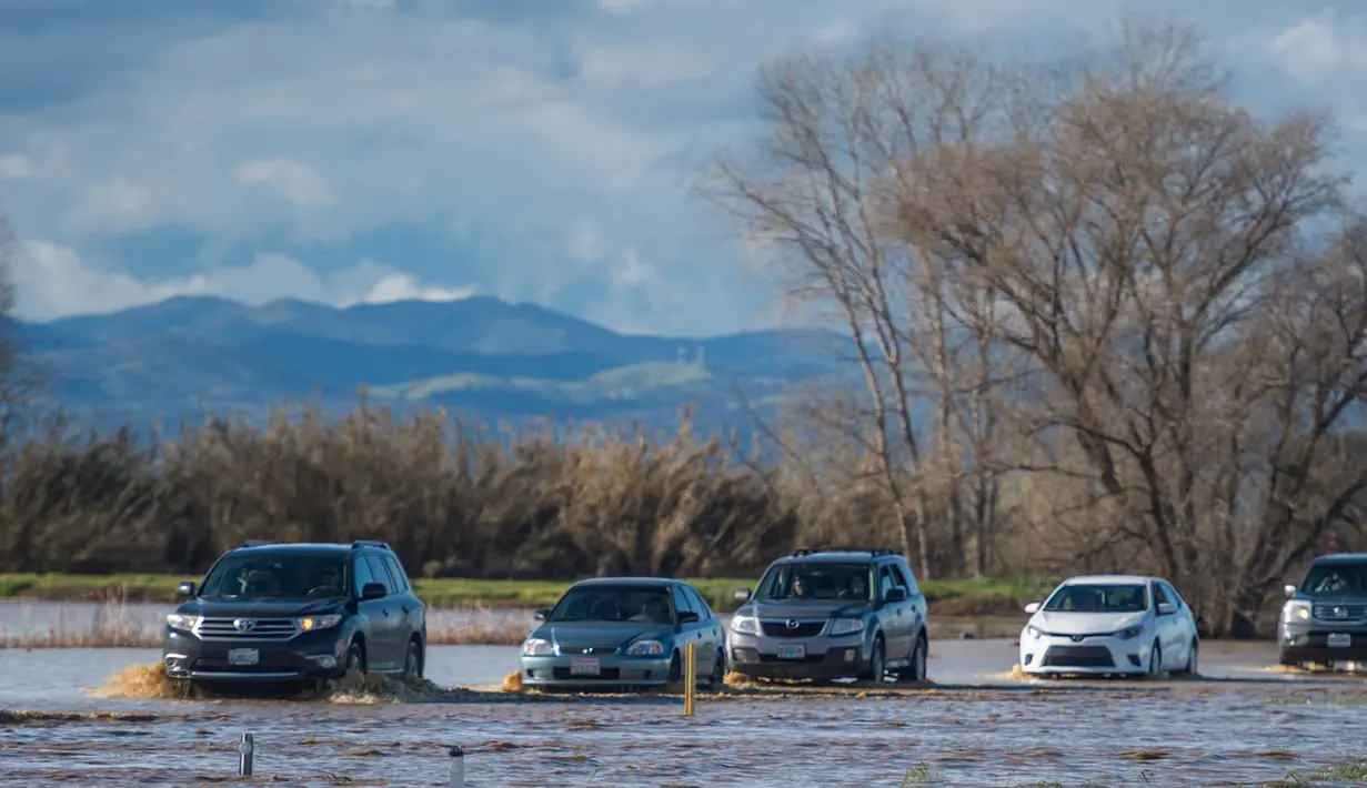 Sejumlah kendaraan melintasi banjir di Maxwell, California, (18/2). Badai terbesar tersebut bergerak dari kawasan Samudera Pasifik, menghantam California. (Andrew Seng/The Sacramento Bee via AP)