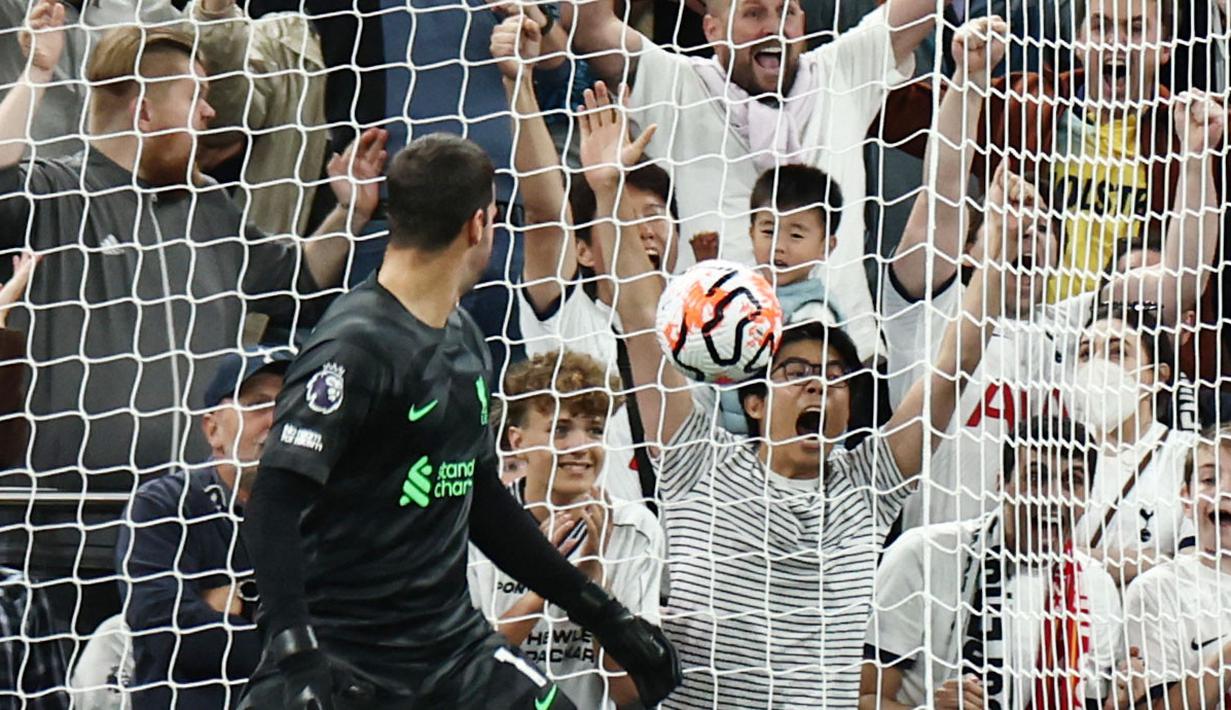 Kiper Liverpool, Alisson Becker, hanya mampu memandangi bola yang masuk ke gawangnya saat melawan Tottenham Hotspur pada laga pekan ketujuh Premier League 2023/2024 di Tottenham Hotspur Stadium, Sabtu (30/09/2023). (AFP/Henry Nicholls)