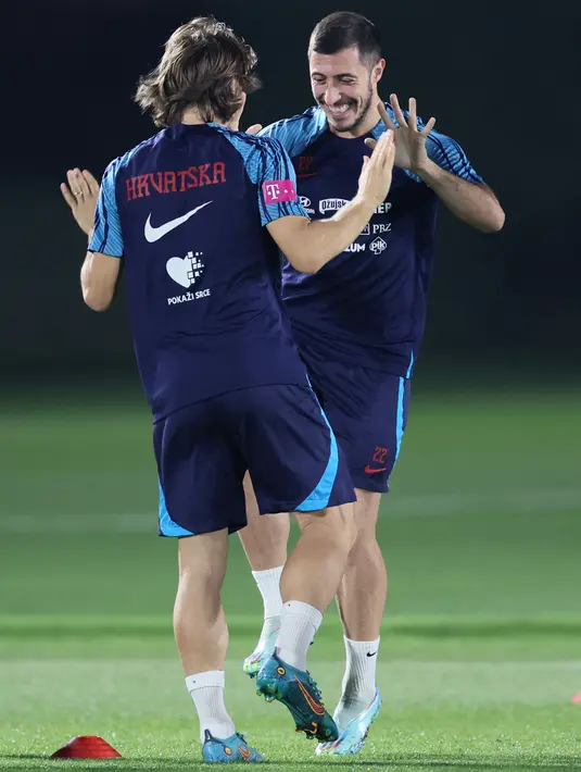 Pemain Kroasia Luka Modric dan Josip Juranovic ambil bagian dalam sesi latihan jelang bertemu Brasil pada perempat final Piala Dunia 2022, di Al Erssal Training Site 3 di Doha, Kamis (7/12/2022). Dalam sejarah piala dunia, dikutip dari FIFA kedua tim baru bertemua dua kali. Brasil berhasil menang di seluruh pertandingan. (JACK GUEZ / AFP)