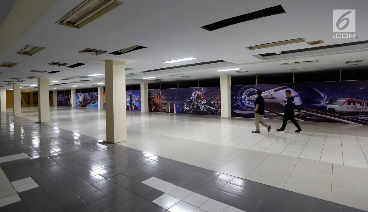 Dua orang pria berjalan di depan papan iklan di Blok M Mal, Jakarta Selatan, Selasa (8/1). Berkembangnya dan maraknya pusat perbelanjaan di Ibukota, membuat Jakarta Blok M Mal semakin sepi dan berkurangnya minat pengunjung. (Liputan6.com/Johan Tallo)