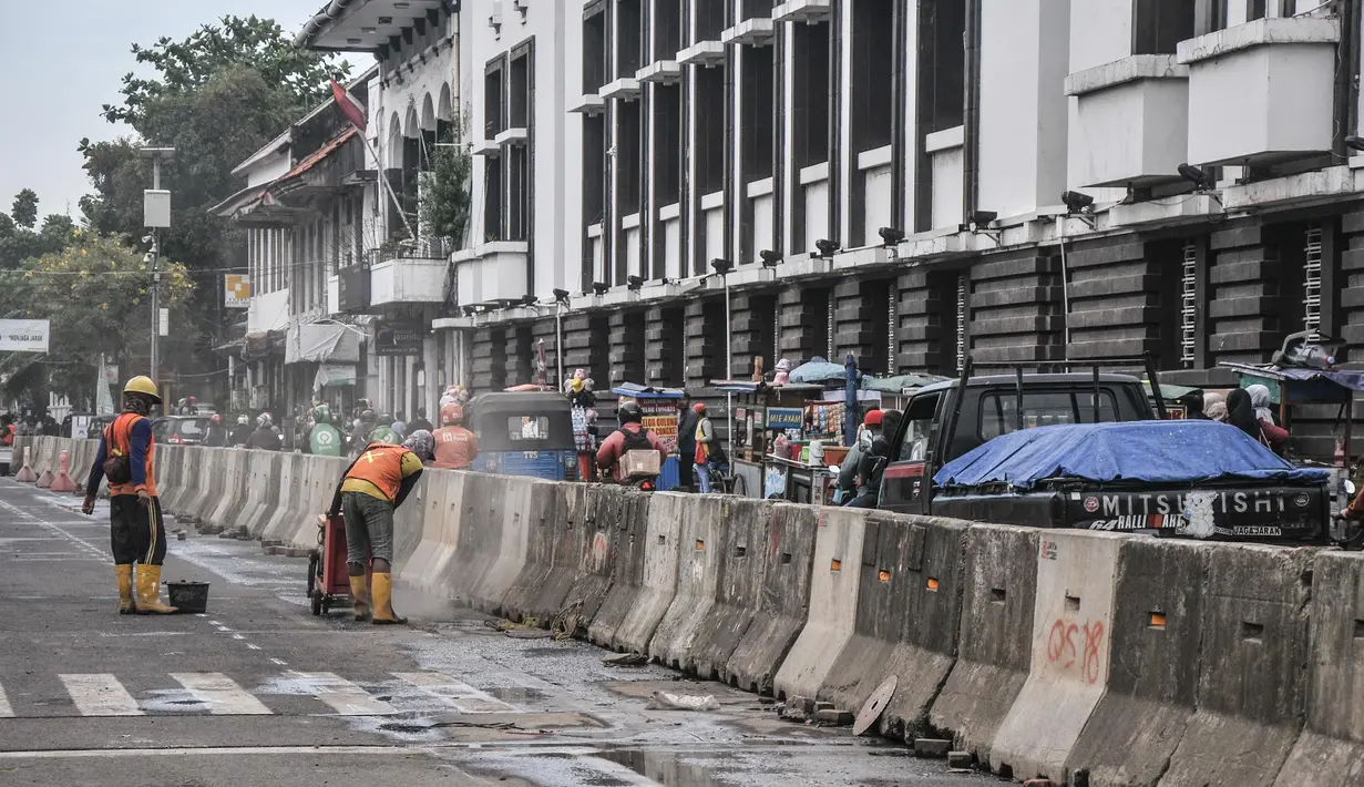 Aktivitas pekerja menyelesaikan proyek revitalisasi fasilitas pejalan kaki atau pedestrian kawasan Kota Tua, Jakarta, Minggu (27/3/2022). Jalur pedestrian itu akan diubah menjadi plaza pedestrian yang lebar sebagai bagian dari penataan kawasan Kota Tua yang rendah emisi (merdeka.com/Iqbal S Nugroho)