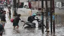 Pengendara motor mendorong kendaraannya melintasi genangan air ketika banjir merendam Jalan KH. Hasyim Ashari, Tangerang, Banten, Sabtu (16/7/2022). Hujan deras mengguyur sejak Jumat siang hingga Sabtu pagi. (Liputan6.com/Angga Yuniar)