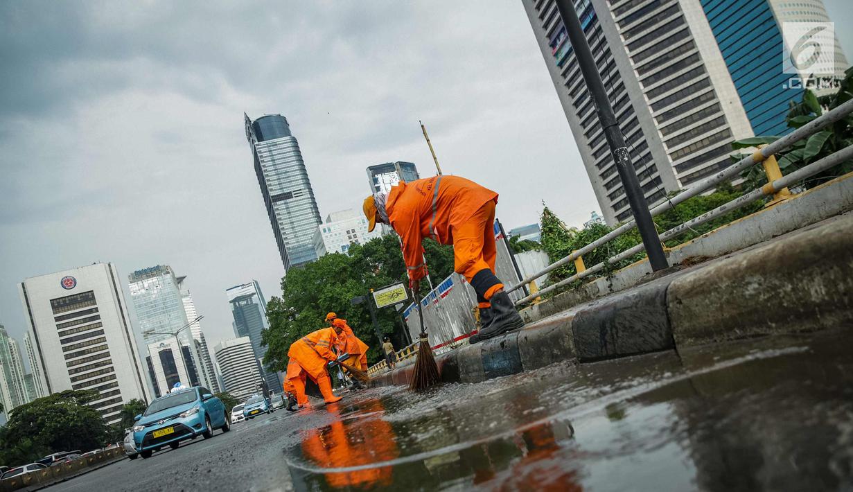Petugas Dinas Kebersihan membersihkan genangan air usai hujan di kawasan jalan Sudirman, Jakarta, Rabu (22/11). Buruknya sistem drainase membuat petugas membersihkan genangan setiap kali hujan, meski dengan peralatan seadanya. (Liputan6.com/Faizal Fanani)