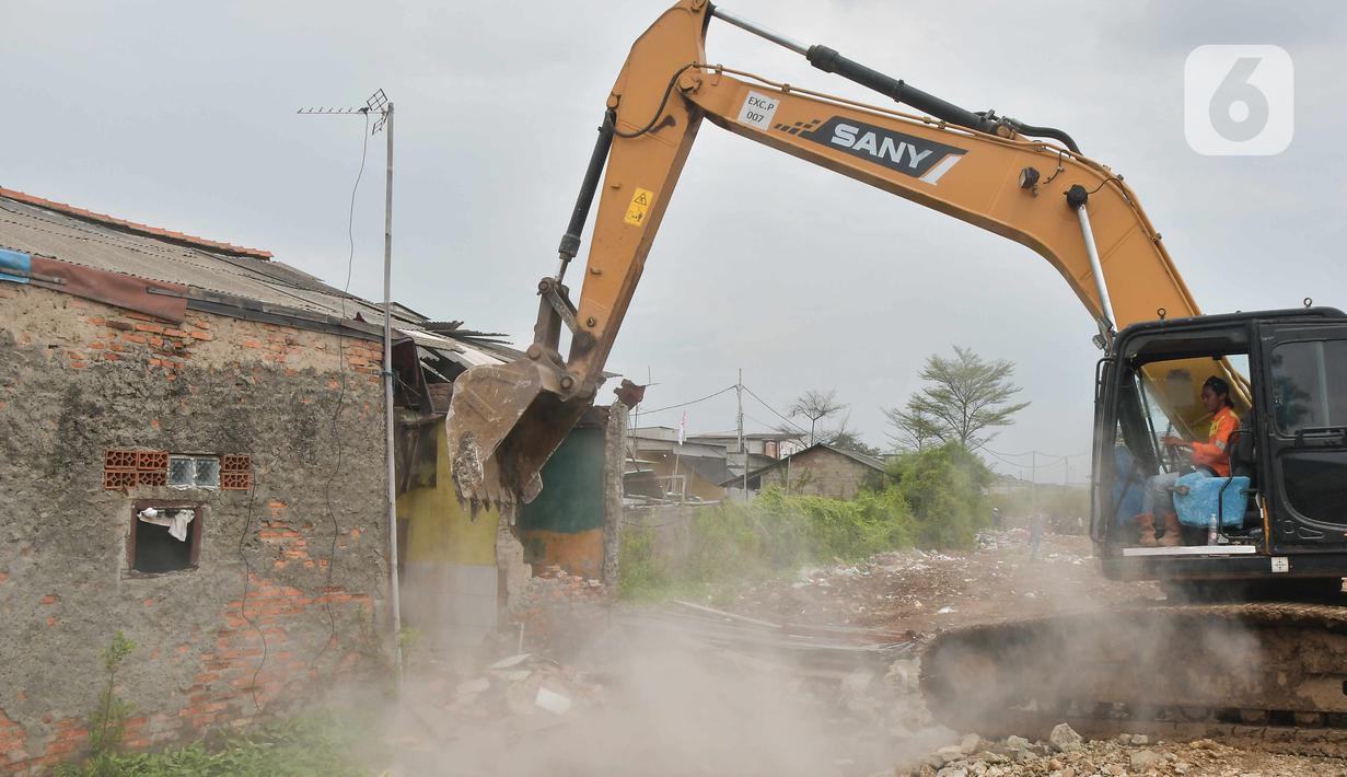 Petugas menggunakan alat berat saat pembebasan lahan proyek Jalan Tol CIbitung-CIlincing seksi 4 di kawasan Semper Timur, Cilincing, Jakarta Utara, Selasa (8/11/2022).  PT Cibitung Tanjung Priok Port Tollways (CTP Tollways) sebagai Badan Usaha Jalan Tol (BUJT) mencatat progres pembebasan lahan untuk seksi 4 sepanjang 7,28 km telah mencapai 100% dan ditargetkan pembangunannya selesai pada akhir tahun 2022. (Liputan6.com/Herman Zakharia)