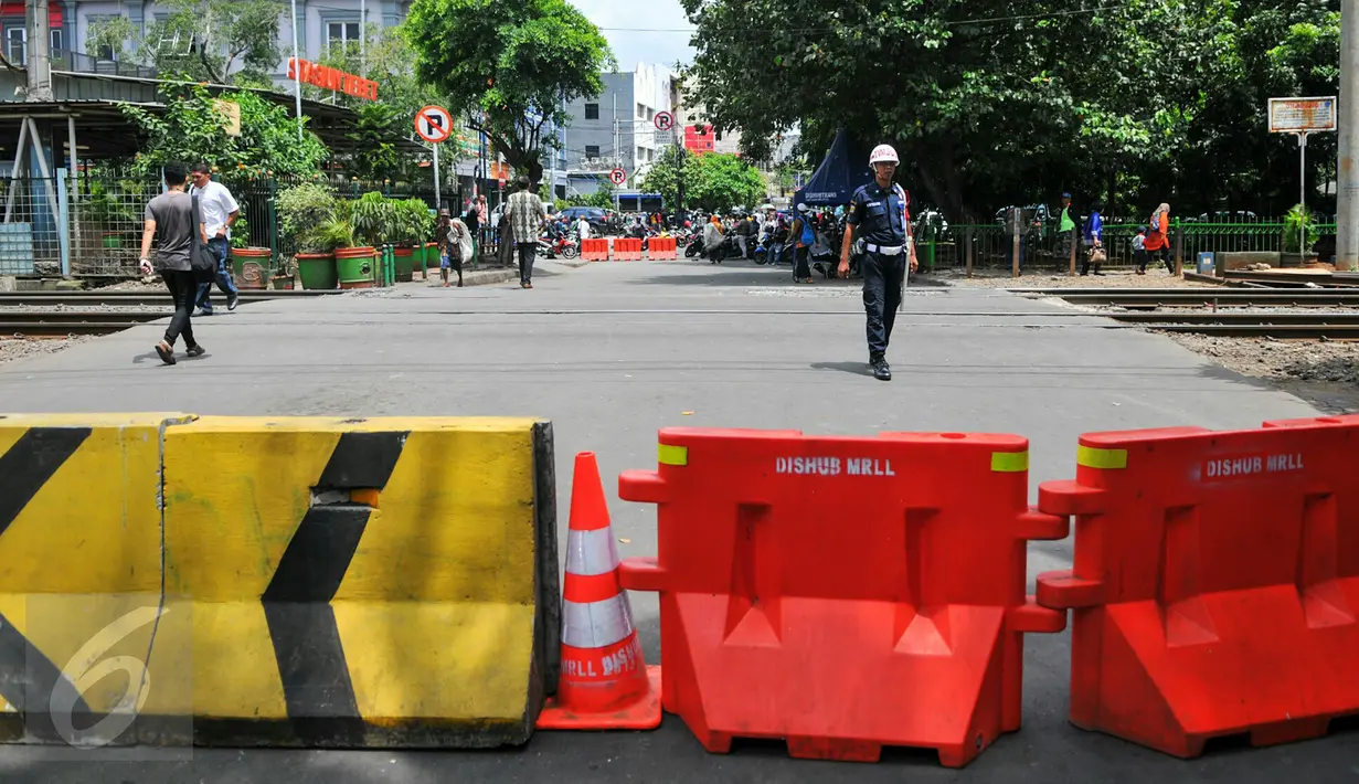 Pejalan kaki menyebrang melewati perlintasan kereta api Stasiun Tebet, Jakarta, Kamis (7/4). Dishubtrans DKI melakukan uji coba penutupandan pengalihan arus lalu lintas di bawah flyover Tebet tepat depan Stasiun Tebet. (Liputan6.com/Yoppy Renato)
