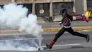 Demonstran berusaha menendang gas air mata saat bentrokan di Caracas, Venezuela, (6/4). Banyak yang menilai Keputusan Mahkamah Agung tersebut dinilai sebagai langkah menuju kediktatoran. (AP Photo / Ariana Cubillos)