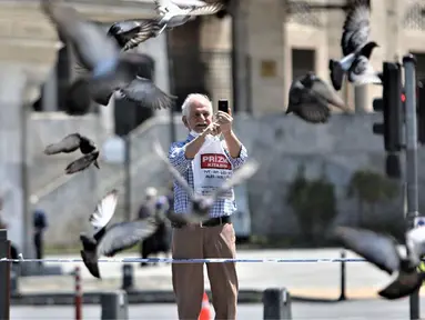 Seorang lansia mengabadikan gambar di Istanbul, Turki, Minggu (10/5/2020). Setelah melonggarkan lockdown terkait virus corona COVID-19, Turki mengizinkan para lansia berusia 65 tahun ke atas untuk keluar rumah.