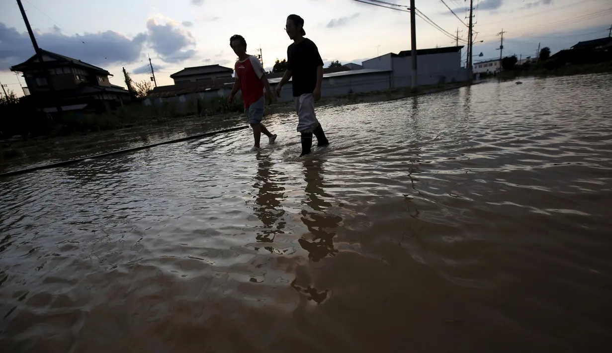 Warga melintasi daerah perumahan yang tergenang air akibat meluapnya sungai Kinugawa yang disebabkan Topan Etau di Joso, Ibaraki Prefecture, Jepang, Sabtu (12/9/2015). Setidaknya 16 orang masih dinyatakan hilang. (REUTERS/Issei Kato)