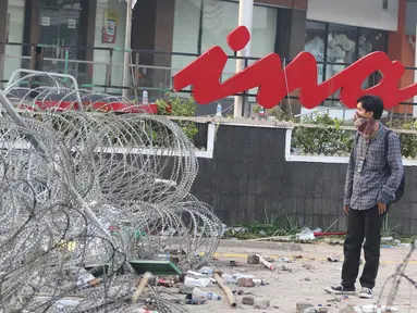 Seorang pria berdiri di depan gedung Sarinah, Jakarta, pascarusuh polisi dan massa, Kamis (23/5/2019). Kerusuhan di sekitar Bawaslu pada 22 Mei 2019 malam menyisakan kerusakan di berbagai titik, salah satu yang jadi korban adalah logo 'Sarinah' yang ikonik. (Liputan6.com/Herman Zakharia)