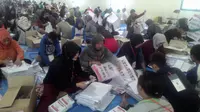 Tenaga sukarelawan tengah melakukan pelipatan surat suara (Liputan6.com/Jayadi Supriadin)