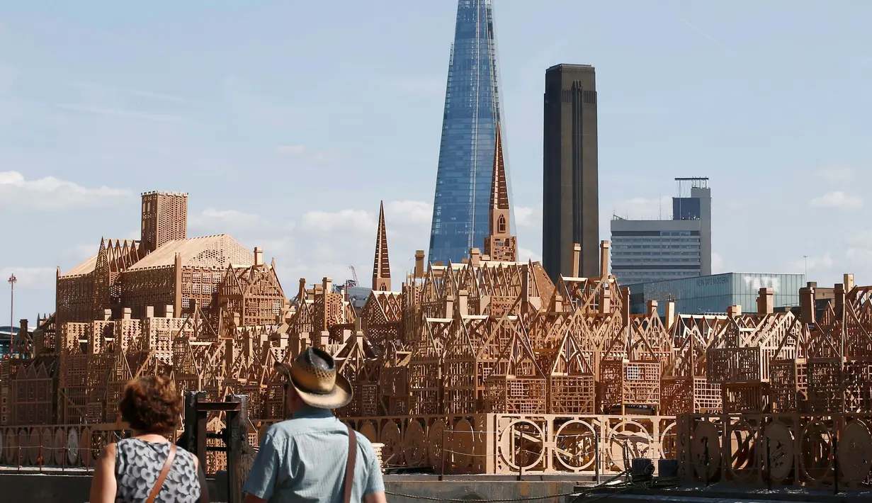 Pejalan kaki melintas di dekat patung skyline Kota London sepanjang 120 meter di London, Inggris, (30/8). Patung ini akan dibakar dalam sebuah acara untuk mengenang bencana Kebakaran besar London pada 1666. (REUTERS/Peter Nicholls)