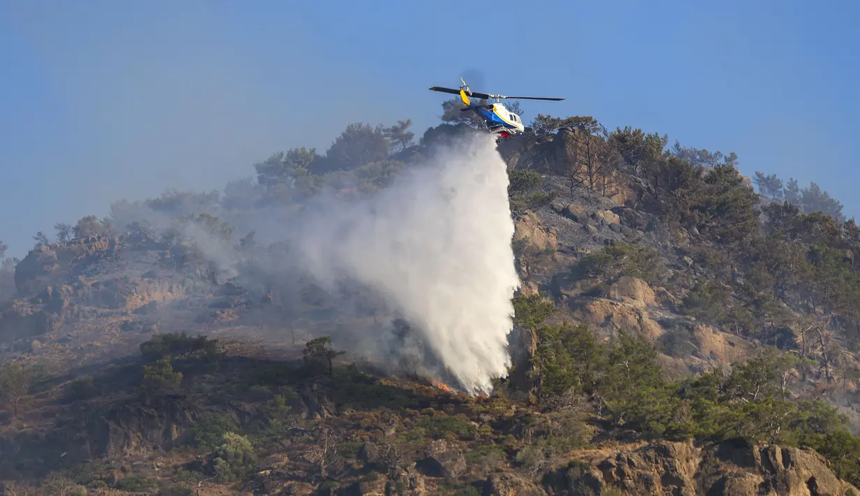 Sedikitnya 230 petugas pemadam, bersama 46 unit mobil pemadam dan helikopter, dikerahkan untuk mengendalikan kobaran api yang muncul sehari sebelumnya. (Costas Metaxakis/AFP)