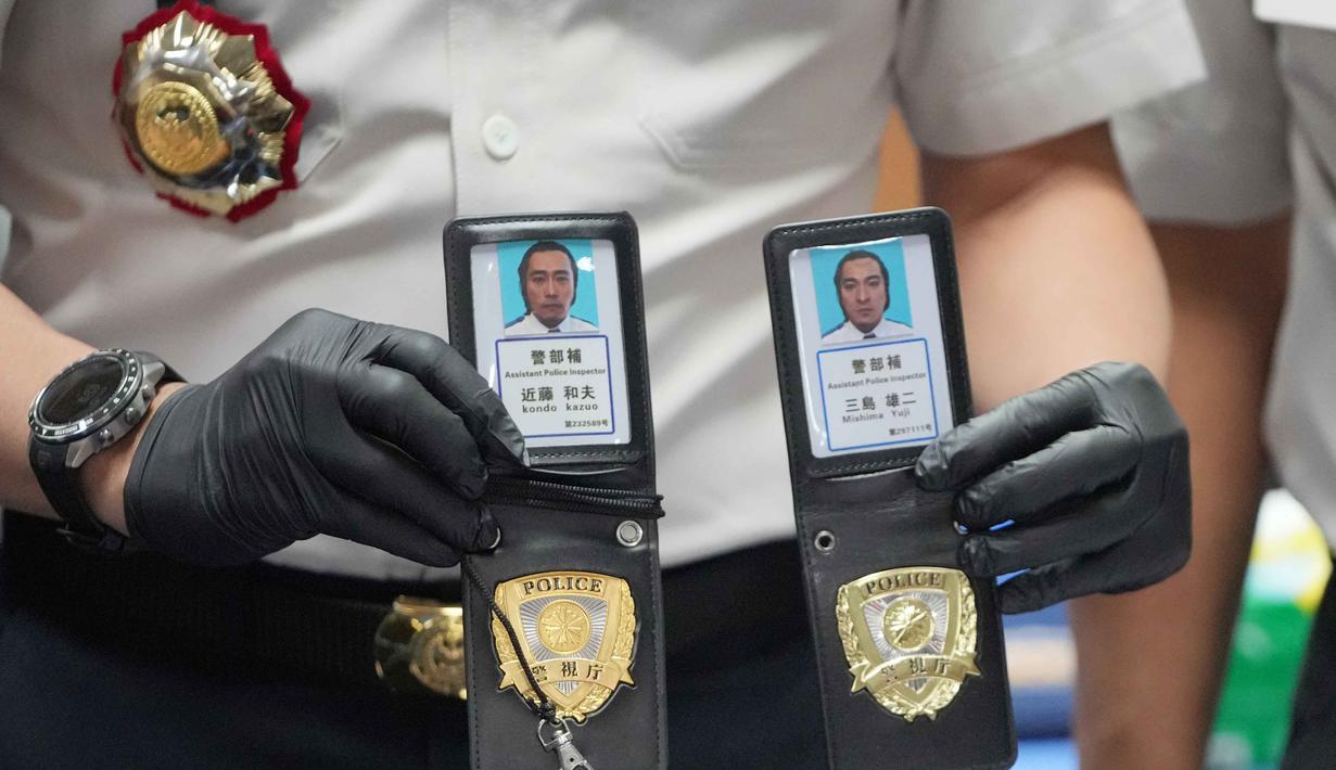 Dari penggeledahan, petugas menyita sejumlah barang bukti yang memperkuat dugaan adanya aktivitas cyber crime, di antaranya atribut yang menyerupai seragam dan tanda pengenal Kepolisian Jepang; puluhan unit telepon genggam dan perangkat komputer; perangkat penguat (booster) serta pengacak sinyal; serta berbagai perangkat elektronik pendukung lainnya. Tampak dalam foto, seorang petugas Imigrasi menunjukkan lencana polisi Jepang palsu yang disita dari warga negara Jepang yang diduga terlibat dalam sindikat penipuan daring (online), di Bogor, Jawa Barat, Rabu 4 Maret 2026. (AP Photo/Achmad Ibrahim)