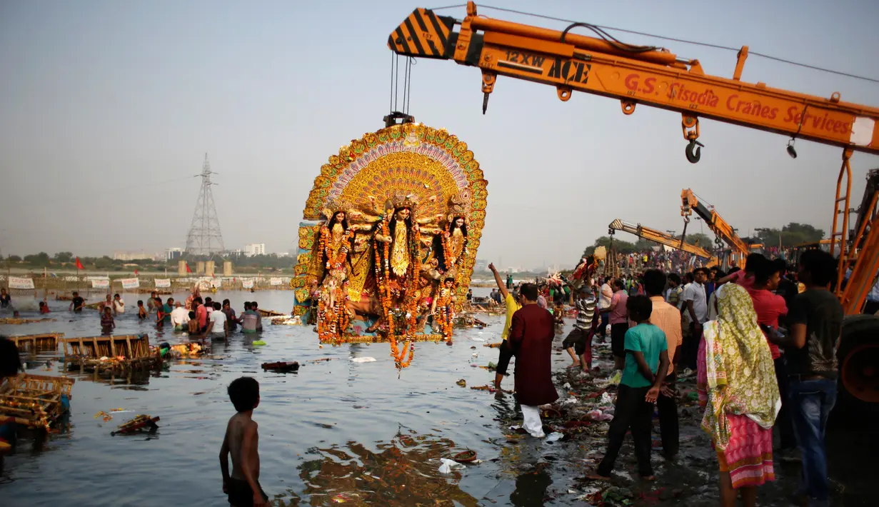 Sebuah patung raksasa dewi Durga diangkat menggunakan alat berat sebelum di tenggalamkan di sungai Yamuna selama festival Durga Puja di New Delhi, India (11/10). Ditenggelamkannya patung ini menandai berakhirnya festival Durga Puja. (AP Photo/Altaf Qadri)