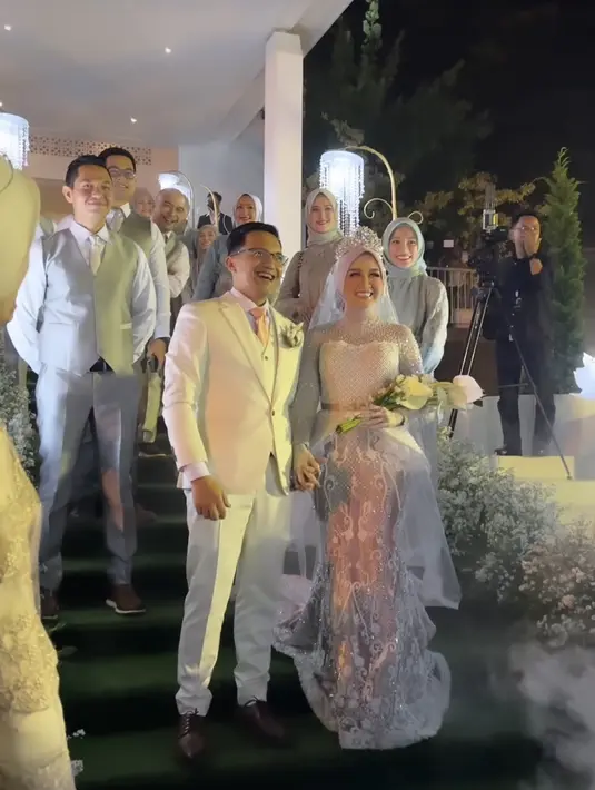 Saat resepsi, ia menyempurnakan gaun pengantinnya dengan tiara. Membuat keseluruhan look semakin stunning. Sahrul Gunawan sendiri memakai setelan jas tiga potong warna putih. (Foto: Instagram @rya_baraba)