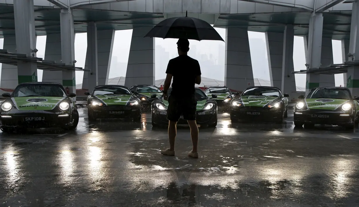 Fotografer saat mengatur armada GrabTaxi yang terdiri dari tujuh mobil mewah untuk pemotretan sebelum beroperasi di Singapura, Selasa (15/9). Mobil-mobil mewah itu akan melayani penumpang secara gratis selama musim balapan F1. (REUTERS/Edgar Su)