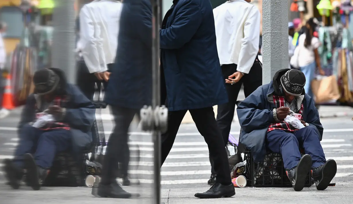 Orang-orang berjalan melewati seorang tunawisma di New York City pada Kamis (17/9/2020). Sejak pandemi virus corona, para tunawisma kini lebih terlihat seiring banyaknya penutupan banyak tempat penampungan karena alasan kesehatan. (Angela Weiss / AFP)