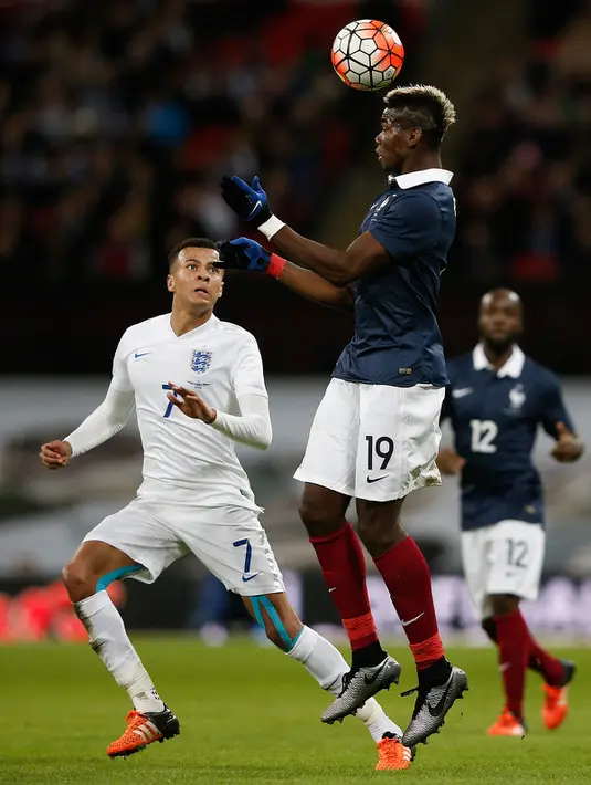 Gelandang Prancis, Paul Pogba berusaha mengontrol bola dengan kepalanya dari kejaran Gelandang Inggris, Dele Alli pada laga persahabatan di Stadion Wembley, London, (18/11). Inggris menang atas Prancis dengan skor 2-0. (AFP PHOTO/ADRIAN DENNIS)