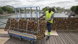 Seorang pekerja memindahkan gembok cinta di Jembatan Pont des Arts di atas Sungai Seine, Paris, Perancis, Senin (1/6/2015). (REUTERS/Philippe Wojazer)