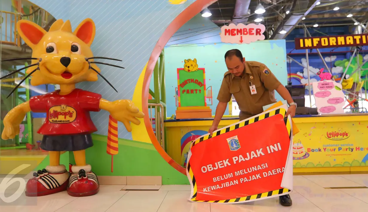 Seorang petugas saat akan memasang stiker penunggak pajak di wahana bermain anak di pusat perbelanjaan di kawasan Senayan, Jakarta, Senin (5/9). Pemasangan stiker dilakukan Dinas Pelayanan Pajak DKI lantaran menunggak pajak. (Liputan6.com/Angga Yuniar)