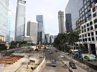 Kendaraan melintasi Jalan Sudirman yang lengang di Jakarta, Minggu (1/5). Berbeda dengan pelaksanaan sebelumnya, Hari Buruh 2016 tidak menyebabkan kemacetan di Jalan Sudirman. (Liputan6.com/Immanuel Antonius)