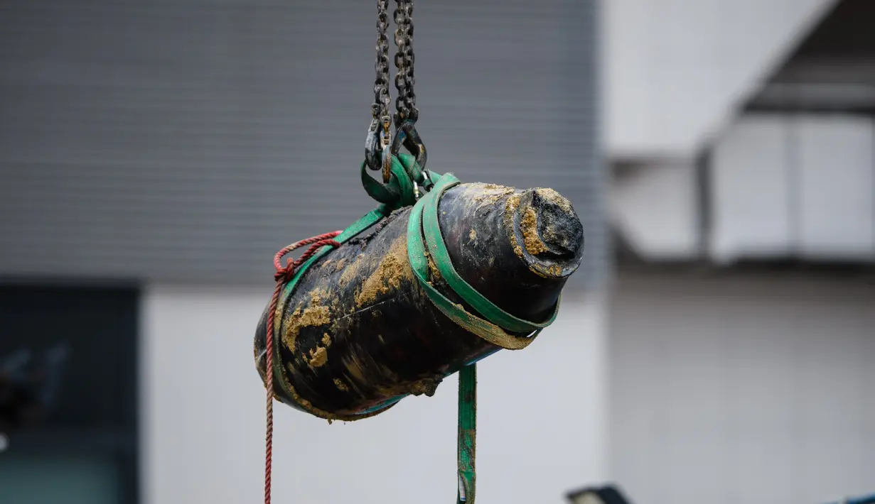 Alat berat mengangkat bom era Perang Dunia II yang ditemukan di lokasi konstruksi di distrik padat Wan Chai, Hong Kong, Kamis (1/2). Para ahli bekerja semalaman untuk menjinakkan bom seberat 450 kg tersebut. (AFP/ Anthony WALLACE)