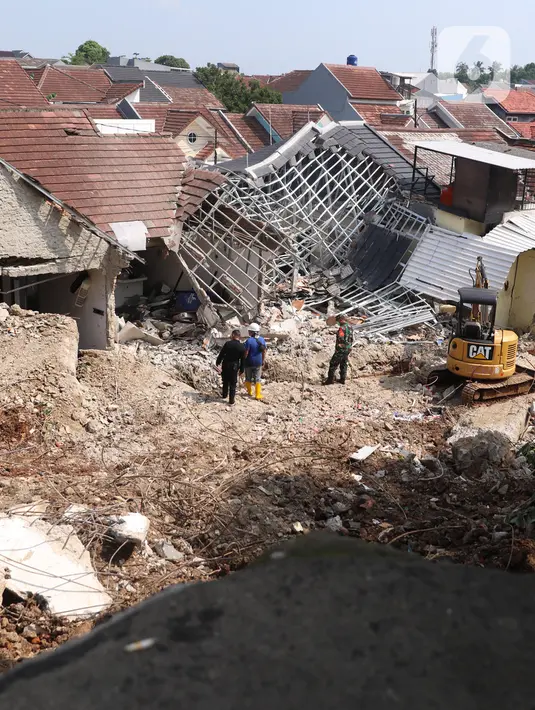 Petugas berada dekat rumah yang hancur tertimpa tanah longsor di Perumahan Nerada Estate Ciputat, Tangerang Selatan, Sabtu (12/6/2021). Tidak ada korban jiwa dalam peristiwa longsor yang menimpa sejumlah rumah akibat hujan deras yang terus menerus di kawasan tersebut. (Liputan6.com/Angga Yuniar)