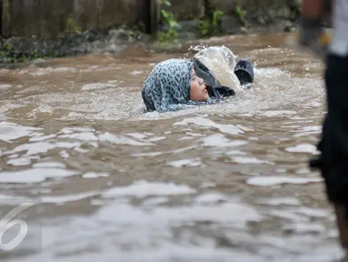 Seorang wanita terperosok ke dalam lubang saat melintasi banjir di Jalan Taman Bukit Duri, Jakarta Selatan, Selasa (21/2). Banjir yang menutupi jalan membuat lubang tak terlihat. (Liputan6.com/Yoppy Renato)