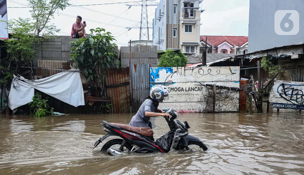 Pengendara motor mendorong kendaraannya yang mogok akibat memaksa menerobos banjir yang menggenangi Jalan KH Hasyim Ashari, Kota Tangerang, Banten, Selasa (4/3/2025). (Liputan6.com/Angga Yuniar)