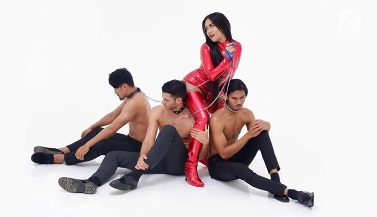 Penyanyi Denada mengenakan baju merah ketat dan sepatu boot berwarna senada. bersama tiga laki-laki yang sedang duduk dalam kondisi topless denada bergoyang di single terbarunya bertajuk "Mutha Futha". (Instagram/@denadaindonesia)