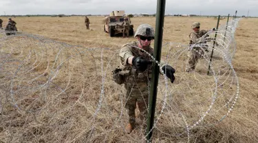 Tentara AS memasang kawat duri dekat jembatan perbatasan antara AS dengan Meksiko di Donna, Texas, Minggu (4/11). Presiden AS Donald Trump mengatakan kehadiran pasukannya untuk mengantisipasi 'invasi' imigran. (AP Photo/Eric Gay)