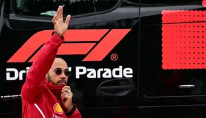 Pembalap Ferrari,  Lewis Hamilton, melambaikan tangan ke fans saat parade pembalap sebelum balapan F1 GP Inggris di Sirkuit Silverstone, Minggu (6/7/2025). (AFP/Ben Stansal)