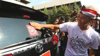 Gubernur Jawa Tengah Ganjar Pranowo menempelkan stiker antikorupsi di mobil dinas. (Dok.@Humasjateng)