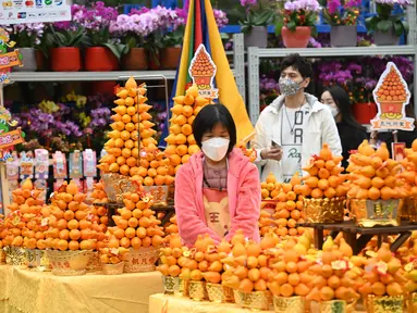 Pengunjung melihat tanaman dan bunga pada hari pembukaan pasar bunga di Hong Kong (16/1/2023). Menjelang Tahun Baru Imlek yang menandai tahun Kelinci pasar bunga di Hong Kong mulai ramai di kunjungi pengunjung. (AFP/Peter Parks)