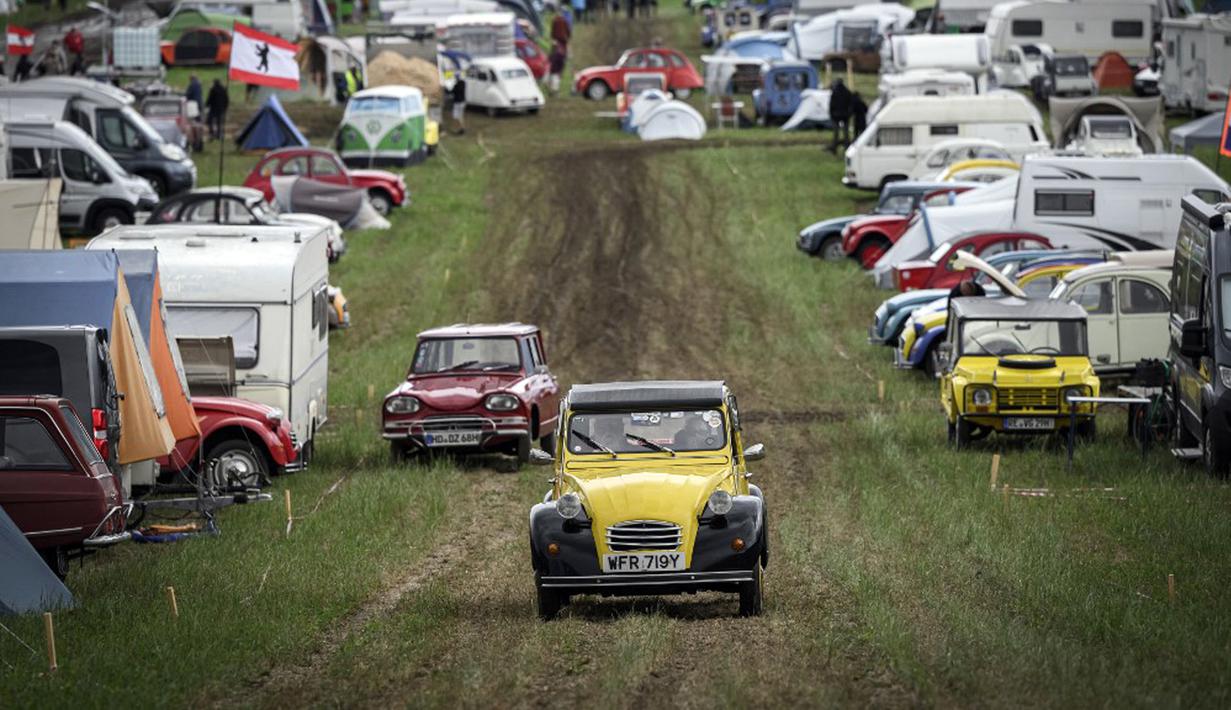 Mobil-mobil melewati kamp selama pertemuan dunia Citroen 2CV Friends di dekat Delemont, Swiss, 26 Juli 2023. (GABRIEL MONNET/AFP)