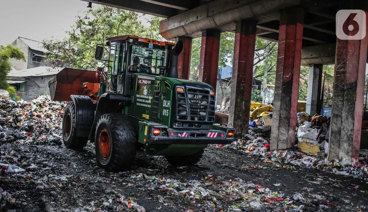 Petugas PPSU menggunakan kendaraan alat berat untuk mengangkut tumpukan sampah di kolong tol Wiyoto Wiyono, Tanjung Priok, Jakarta, Selasa (5/11/2019). Dalam sehari, petugas mengangkut sampah hingga 10 truk dengan berat total sekitar 100 ton ke TPA Bantar Gebang. (Liputan6.com/Faizal Fanani)