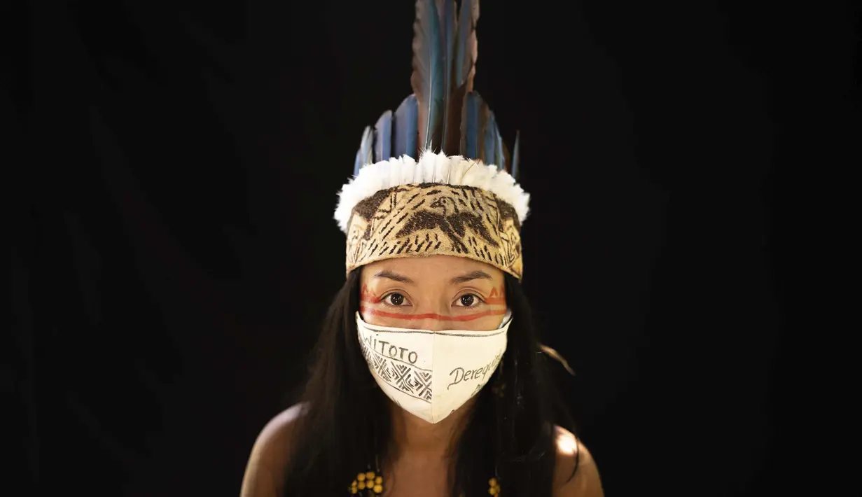 Vanda Ortega (33) dari kelompok etnis pribumi Witoto mengenakan pakaian tradisional sukunya dan masker saat pandemi virus corona COVID-19 di Taman Suku, Manaus, Brasil, Minggu (31/5/2020). Ortega telah menjadi salah satu simbol perjuangan masyarakat pribumi melawan pandemi. (AP Photo/Felipe Dana)