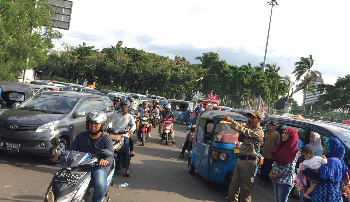 Petugas mengatur kendaraan di sekitar kawasan Monas, Jakarta, Senin (1/1). Kurangnya pengawasan menyebabkan banyak PKL dan parkir liar memenuhi kawasan tersebut sehingga menimbulkan kesemrawutan. (Liputan6.com/Immanuel Antonius)