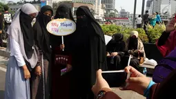 Komunitas Niqab Squad bersama pengunjung CFD berswafoto di kawasan Bundaran HI, Jakarta, Minggu (10/9). Selain melakukan Challenge kegiatan ini juga mengumpulkan donasi untuk Etnis Rohingnya. (Liputan6.com/Johan Tallo)